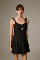 Vestido corto de poliéster color negro con estampado de lunares brillantes tipo strass, tirantes finos con volados, escote con abertura cut-out en el centro y falda con volado fruncido en el borde inferior.