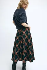 Falda midi de tiro medio, evasé, confeccionada con mezcla de viscosa y diseño de cuadros en tonos verdes, marrones y negros. Cuenta con cierre de cremallera oculta en la costura.