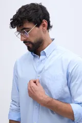 Camisa de manga larga celeste con cuello camisero abotonado, cierre frontal de botones y un bolsillo aplicado en el pecho con logo bordado a tono.