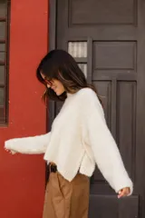 Buzo tejido en mohair de corte crop, con cuello redondo, mangas largas y tajos laterales en el ruedo.