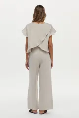 Blusa de lino color beige, de manga corta con volados, cuello redondo y espalda cruzada con volados.