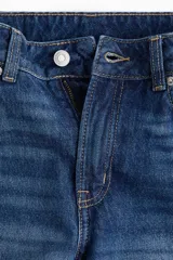 Jeans de cinco bolsillos en denim de algodón lavado, color azul medio. Modelo de tiro alto con piernas rectas de corte holgado y cierre con botón.