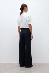 Pantalón sastrero de corte recto y tiro alto, confeccionado en tela con sutil diseño de rayas diplomáticas. Presenta cierre frontal con botón y bolsillos laterales.
