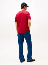 Remera de algodón de corte regular, color rojo, con cuello redondo y mangas cortas. Presenta el logotipo de la marca bordado en el pecho en tipografía cursiva y la bandera distintiva de Tommy Hilfiger bordada en la manga.