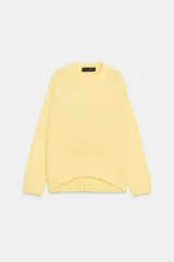 Sweater de punto color amarillo claro, con cuello redondo, manga larga y dobladillo asimétrico más largo en la parte trasera. Presenta acabados en rib en cuello, puños y ruedo.