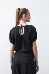 Top negro de manga corta con escote redondo y frunces en la costura de la sisa, creando un efecto de manga abullonada. El tejido parece ligero y con textura.