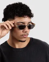 Lentes de sol con marco rectangular plateado y lentes oscuros.