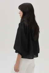 Blusa blanca con lunares en relieve, cuello con volados y lazos, mangas abullonadas 3/4 y bordados con lentejuelas en el frente.