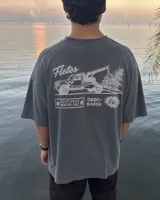 Remera oversize de color verde militar con efecto acid wash y diseño estampado en la espalda que incluye un camión de remolque y texto alusivo.