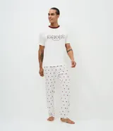 Pijama largo para hombre compuesto por una remera de manga corta blanca con cuello redondo bordó y estampa frontal de dados con la leyenda 'Lucky to Have You', y un pantalón largo blanco con estampado full print de corazones bordós y cintura elástica.
