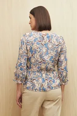 Blusa celeste con estampado floral en tonos beige y marrón, escote en V, mangas 3/4 abullonadas y frunce en la cintura.