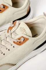 Zapatillas deportivas color beige con detalles en cuero marrón y suela de goma blanca y marrón.