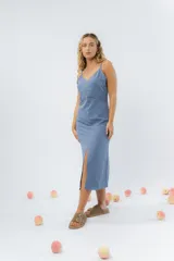Vestido midi celeste de tejido tipo seda fría, con breteles finos regulables, botones de madera decorativos en el frente, pliegues decorativos en la cintura y cierre invisible en el costado.