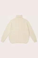 Polera de cuello alto con diseño oversize, manga larga y dobladillo asimétrico con corte redondeado en la parte frontal.