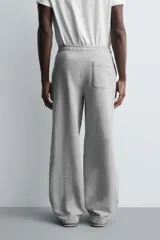 Pantalón jogger de corte relajado y pernera ancha, confeccionado en tejido de algodón con interior perchado. Cuenta con cintura elástica ajustable mediante cordón interior, bolsillos laterales y un bolsillo trasero de plastrón.