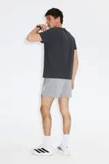 Remera deportiva para running de color gris oscuro, confeccionada en tejido técnico con tecnología DryMove. Presenta cuello redondo, mangas cortas, detalles reflectantes en los hombros y aberturas laterales en el bajo.