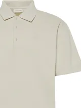 Chomba Calvin Klein de corte relajado, confeccionada en tejido de punto acanalado color beige. Presenta cuello clásico, cartera con tres botones y logo de la marca bordado sutilmente en el pecho.