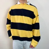 Buzo de manga larga con diseño a rayas horizontales amarillas y negras, corte boxy y cuello polo blanco con abertura en V.