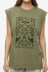 Musculosa color crudo con estampado frontal de paisaje montañoso y texto "EXPLORING Outlands", corte holgado y aberturas laterales en el ruedo.
