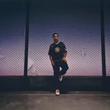 Camiseta Nike Total 90 Energy de color negro, con detalles en amarillo flúor y verde, de manga corta y cuello en V. Presenta un diseño inspirado en los años 2000 con el número 90 impreso en el centro del pecho y ribetes curvados en contraste.