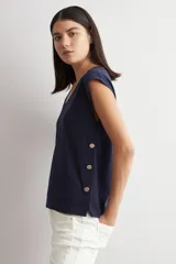 Remera azul marino de manga corta, con corte holgado y detalle de botones metálicos en los laterales.