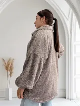 Campera marrón de tela tipo teddy con cierre frontal, cuello alto y bolsillos laterales.