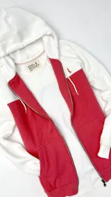 Campera con capucha blanca y cuerpo color salmón, con cierre frontal y bolsillos laterales.