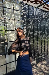 Falda larga azul de tafeta, ajustada en la cintura y con volado amplio con tajo lateral.