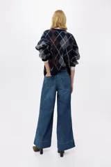 Jean de corte wide leg tiro alto, confeccionado en denim azul con efecto desgastado. Presenta diseño de cinco bolsillos, detalles trenzados a los lados y dobladillo ancho pespunteado.