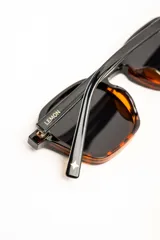 Lentes de sol polarizados con armazón negro de diseño geométrico y lentes oscuros.