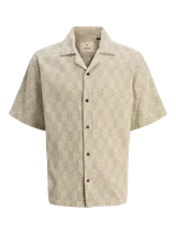 Camisa de manga corta Jack & Jones con cuello resort y cierre de botones. Diseño con estampado de espiga en tonos beige y blanco. Confeccionada en tejido dobby 100% algodón.