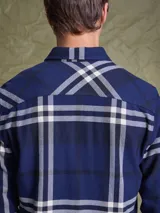 Camisa de manga larga en color azul noche con un patrón de cuadros finos en tonos rojos y verdes. Presenta cuello clásico, cierre frontal con botones y un bolsillo en el pecho con solapa.