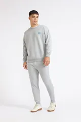 Buzo Quiksilver World Force de color gris melange, con cuello redondo y mangas largas. Presenta un pequeño estampado en el pecho con el logo de la marca en tonos verde y azul.