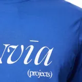 Remera azul con estampa frontal de la marca Rivvia en color blanco y tres flores rojas.