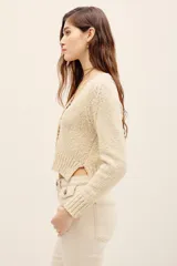 Cardigan de punto color beige, con escote en V y cierre frontal de botones, de mangas largas y corte corto.