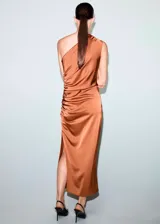 Vestido midi de satén color cobre con diseño asimétrico de un solo hombro. Presenta un detalle fruncido lateral que recorre el costado, cierre de cremallera lateral y una abertura en el bajo.