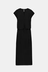 Vestido midi negro con cuello redondo y manga sisa, confeccionado por Zara Woman Collection. Presenta un diseño drapeado en la parte delantera y un bajo asimétrico con un voluminoso volante lateral. Incluye un pequeño cierre de botón en la espalda.