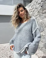 Sweater de tejido de punto en color gris con detalles de bordes en color blanco, de corte holgado y mangas largas.