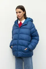 Campera puffer azul de nylon con capucha, dos bolsillos y cierres a tono. Tiene un bolsillo externo adicional con solapa en una de las mangas.