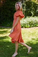 Vestido azul con escote redondo, mangas cortas abullonadas con elástico, espalda descubierta y largo asimétrico.