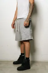 Bermuda estilo baggy de algodón color gris melange, con cintura elástica y cordón de ajuste de color crudo. Presenta un gran logo bordado en blanco en la pierna derecha.