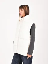 Chaleco puffer gris claro, con cuello alto y cierre frontal.