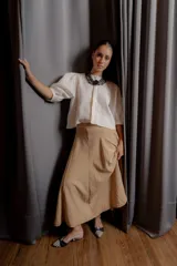 Falda midi de corte amplio y caída suave, color beige, con cintura elástica y bolsillos laterales.