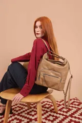 Cartera mochila color tostado, de cuero sintético, con compartimento principal amplio y bolsillos frontales con cierre. Tiene correas ajustables y asa superior para llevar al hombro o como mochila.