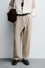 Pantalón de corte relajado confeccionado en tejido con mezcla de lyocell. Presenta cintura con trabillas, cierre frontal con cremallera y botón, pliegues en el delantero, bolsillos laterales y bolsillos traseros de vivo.