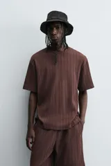 Camiseta de algodón de corte relajado (relaxed fit) color marrón oscuro, con cuello redondo y manga corta. Presenta una textura acanalada vertical tipo jacquard.