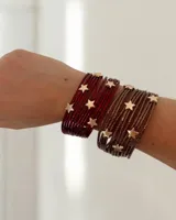 Brazalete de múltiples tiras finas con acabado metalizado, decorado con apliques de estrellas doradas y cierre imantado.