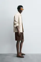 Bermuda de algodón color beige claro, de corte regular fit, con cintura elástica ajustable mediante cordón. Presenta bolsillos laterales y un bolsillo trasero de vivo.