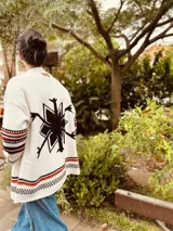 Cardigan tejido artesanalmente en lana color crudo, con diseño de copo de nieve en la espalda y bordados a mano.