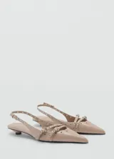 Zapato color beige con punta, cierre de hebilla, detalles troquelados y tacón kitten.